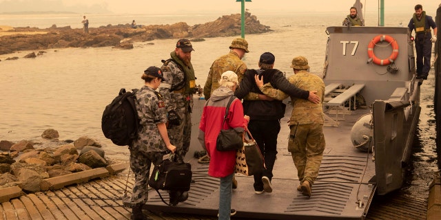 In this photo released by the Australian Department of Defense, evacuees board landing craft to be ferried out to the navy's HMAS Choules, Friday, Jan. 3, 2020, in Mallacoota, Victoria, Australia.