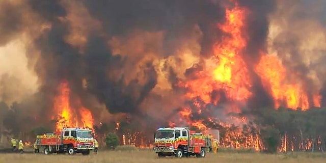 In this image dated Dec. 30, 2019, and provided by NSW Rural Fire Service via their twitter account, firefighters are seen as they try to protect homes around Charmhaven, New South Wales.  (Twitter@NSWRFS via AP)