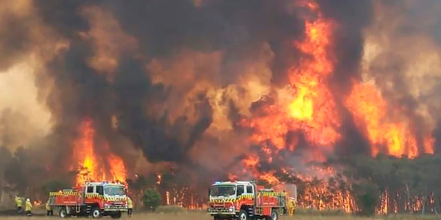 In this image dated Dec. 30, 2019, and provided by NSW Rural Fire Service via their twitter account, firefighters are seen as they try to protect homes around Charmhaven, New South Wales.  (Twitter@NSWRFS via AP)