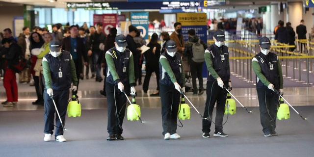 Workers spray antiseptic solution on the arrival lobby amid rising public concerns over the possible spread of a new coronavirus at Incheon International Airport in Incheon, South Korea, Tuesday, Jan. 21, 2020. 