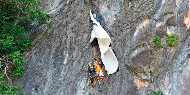 In this image released by the Phattalung Rescue Organization, a base jumper is rescued after his parachute was caught on a rock's edge, Monday, Jan. 13, 2020, in Phattalung, Thailand. An Austrian base jumper, Johannes Grasser, 28, was rescued in southern the Thai province after being stuck on a near vertical cliff for hours when his parachute caught a rock’s edge, almost 200 meters (656 feet) above the around. (Phattalung Rescue Organization via AP)