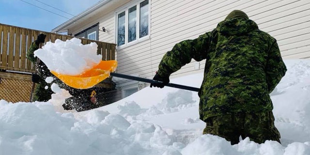 Soldiers from the Canadian Armed Forces can be seen shoveling out a home on Monday.