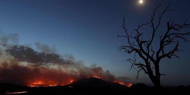 A wildfire threatening property glows at dusk near Clear Range, south of the Australian capital of Canberra on Friday.