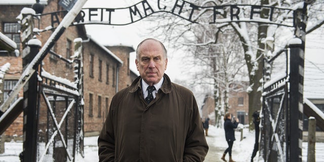 President of the World Jewish Congress Ronald Lauder stands near the lettering "Arbeit macht frei" (work makes you free) at the Auschwitz entrance gate in 2015 (ODD ANDERSEN/AFP via Getty Images)