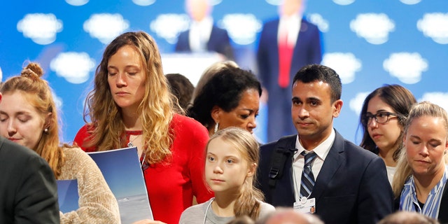 Swedish environmental activist Greta Thunberg, center, leaves as U.S. President Donald Trump, rear right, and Executive Chairman Klaus Schwab, rear left, are seen at the World Economic Forum in Davos, Switzerland, Tuesday, Jan. 21, 2020. The 50th annual meeting of the forum will take place in Davos from Jan. 21 until Jan. 24, 2020. (AP Photo/Markus Schreiber)