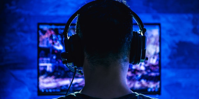 Boy wearing headphones playing video games late at night