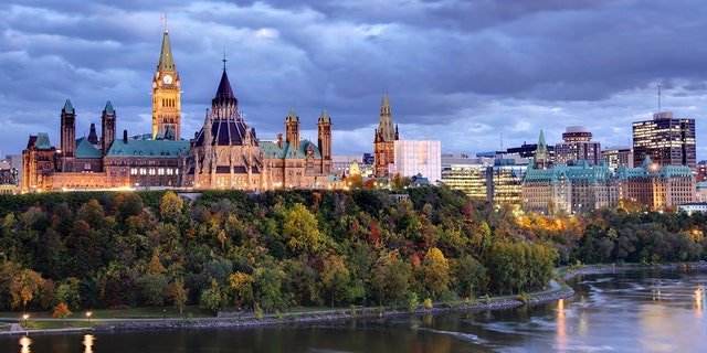 Parliament Hill atop a dramatic hill overlooking the Ottawa River in Ottawa, Ontario, in autumn (iStock)