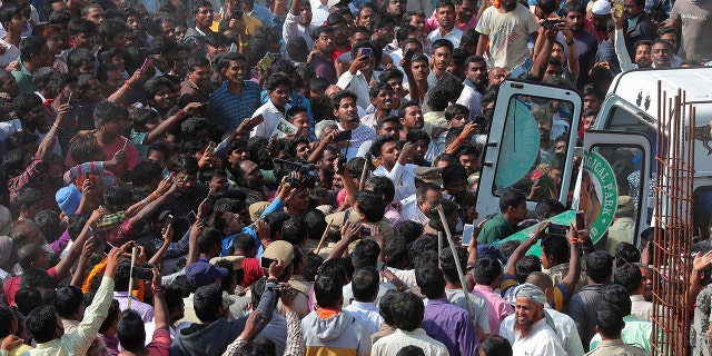Residents swarmed Indian wildlife officials as they carried a tranquilized leopard to catch a glimpse of the big cat. (AP Photo/Mahesh Kumar A.)