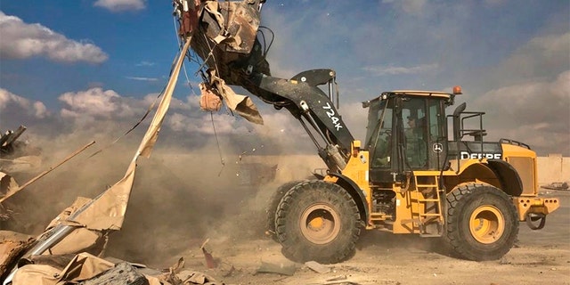 A bulldozer clears rubble and debris at the base. (AP)