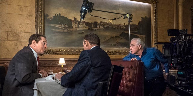 This image released by Netflix shows director Martin Scorsese, right, with actors Robert De Niro, left, and Joe Pesci on the set of 