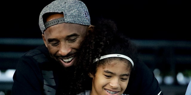 FILE - In this July 26, 2018 file photo former Los Angeles Laker Kobe Bryant and his daughter Gianna watch during the U.S. national championships swimming meet in Irvine, Calif.  (AP Photo/Chris Carlson)