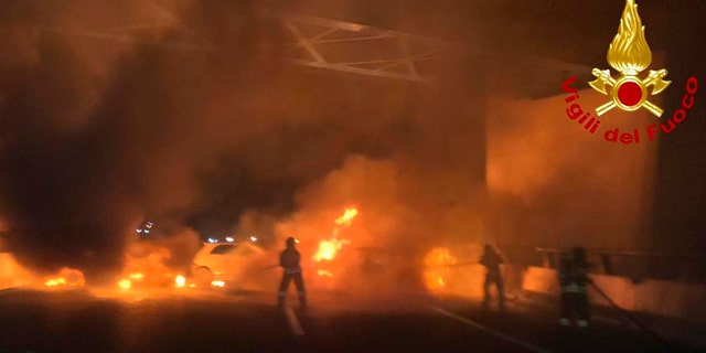 In this photo released by the Italian firefighters, firemen try to extinguish a dozen vehicles on fire on a highway near Milan, Italy, early Wednesday. (AP/Italian Firefighters)