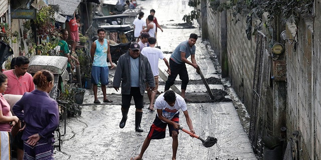 Residents clean ash outside their homes as Taal Volcano still spews ash on Monday Jan. 13, 2020, in Tagaytay, Cavite province, south of Manila, Philippines. (AP Photo/Aaron Favila)