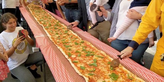 The three-hundred-plus-foot pizza took four hours to create and was then cooked using a conveyor oven.