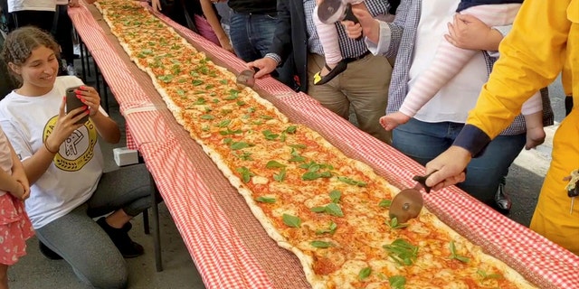 The three-hundred-plus-foot pizza took four hours to create and was then cooked using a conveyor oven.