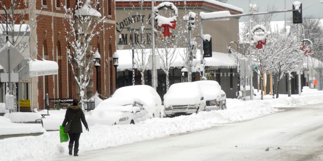 A pedestrian makes her way along a snow-covered Front Street in downtown Port Angeles, Wash., on Wednesday, Jan. 15, 2020, after heavy snow blanketed the city overnight.