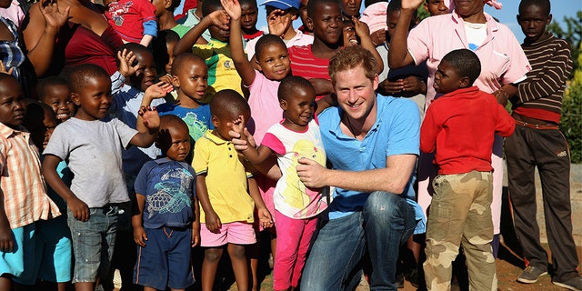 Prince Harry plays with a three year old blind girl named Karabo during a visit to Phelisanong Children's Home on Dec. 6, 2014 in Pitseng, Lesotho.