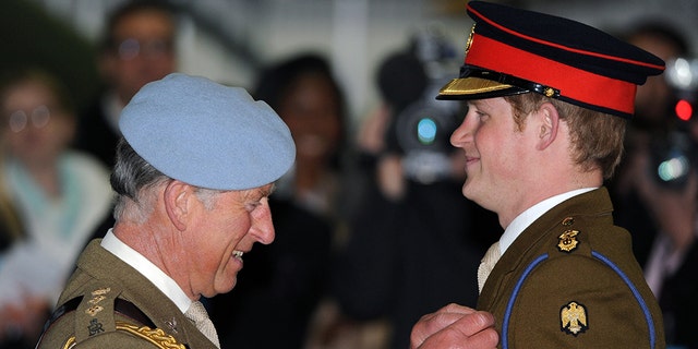 Prince Charles, Prince of Wales, presents Prince Harry with his flying wings and Army Flying Corps blue beret during the Prince Harry Pilot Course graduation ceremony at the Army Aviation Center on May 7, 2010 in Andover, England.