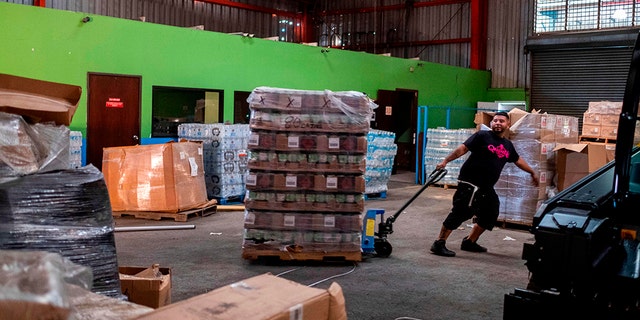 A man pulls a pallet of gas canisters believed to have been from when Hurricane Maria struck the island in 2017 in a warehouse in Ponce, Puerto Rico on Jan. 18, 2020, after a powerful earthquake hit the island. (Photo by Ricardo ARDUENGO / AFP)