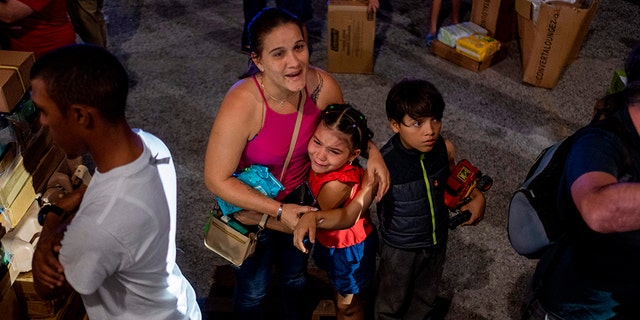 A girl cries next to her mother after police evacuated people breaking into a warehouse filled with supplies, believed to have been from when Hurricane Maria struck the island in 2017 in Ponce, Puerto Rico on Jan. 18, 2020, after a powerful earthquake hit the island. (Photo by Ricardo ARDUENGO / AFP)