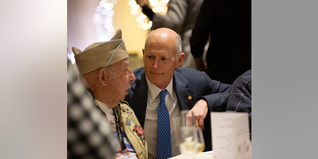 Sen. Rick Scott speaking to a veteran from the 82nd Airborne during a reception commemorating the 75th anniversary of the Battle of the Bulge.