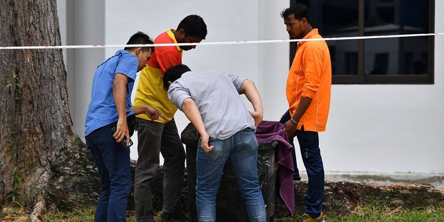 Police officers and cleaners inspect the contents of trash bin after a baby was found alive inside it Tuesday in Singapore.