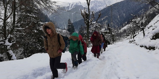 Kashmiri children walk through snow-covered road after heavy snowfall in Neelum Valley, Pakistan-administered Kashmir, Wednesday, Jan. 15, 2020.