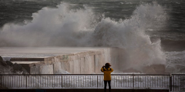 A woman photographs the Mediterranean sea during strong winds in Barcelona, Spain, Monday, Jan. 20, 2020.