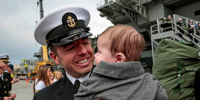 New dad Chief Mass Communication Specialist Mike Lenart holds his child for the first time after the USS Abraham Lincoln came home Monday.