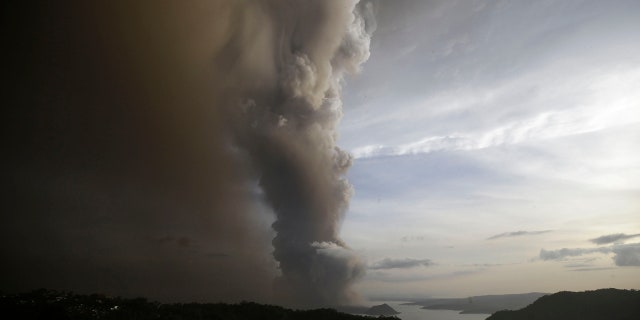 A tiny volcano near the Philippine capital that draws many tourists for its picturesque setting in a lake belched steam, ash and rocks in a huge plume Sunday, prompting thousands of residents to flee and officials to temporarily suspend flights.