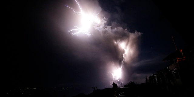 In this Sunday, Jan. 12, 2020, photo, lightning strikes beside the ash cloud as Taal Volcano erupts in Tagaytay, Cavite province, outside Manila, Philippines.