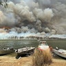 Boats are pulled ashore as smoke and wildfires rage behind Lake Conjola, Australia, Jan. 2, 2020.