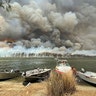 Boats are pulled ashore as smoke and wildfires rage behind Lake Conjola, Australia, Jan. 2, 2020. 