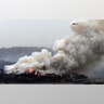 A military helicopter flies above a burning woodchip mill in Eden, New South Wales, Jan 6, 2020.