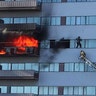 A Los Angeles Fire Department firefighter rescues a man who had climbed out on the side of a 25-story high-rise apartment, escaping flames from a burning apartment in Los Angeles, Jan. 29, 2020. 