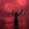 A man watches fireworks exploding over Copacabana Beach during the New Year's celebrations, in Rio de Janeiro, Brazil, Jan. 1, 2020. 