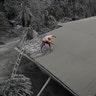 A resident clears volcanic ash from his roof in Laurel, Philippines, Jan. 14, 2020. 