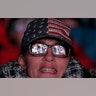 A large screen displaying President Donald Trump speaking is reflected in a woman's glasses outside a rally in Wildwood, New Jersey, Jan. 28, 2020.