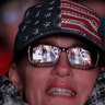 A large screen displaying President Donald Trump speaking is reflected in a woman's glasses outside a rally in Wildwood, New Jersey, Jan. 28, 2020.