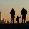 People walk in front of the skyline of lower Manhattan and One World Trade Center as the sun sets in New York City, Jan. 15, 2020.