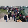 People standing in the cold in a field, as they line up to enter the Wildwoods Convention Center for a campaign rally with President Trump.?