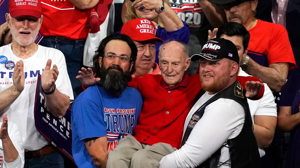 Trump supporters hold up Ervin Julian, a 100-year-old World War II veteran, during a rally supporting President Donald Trump on Wednesday, Feb. 19, 2020 in Phoenix. (AP Photo/Rick Scuteri)