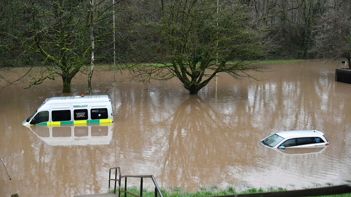 An ambulance, left, and a vehicle are submerged after flooding in Nantgarw, Wales, Sunday, Feb. 16, 2020.