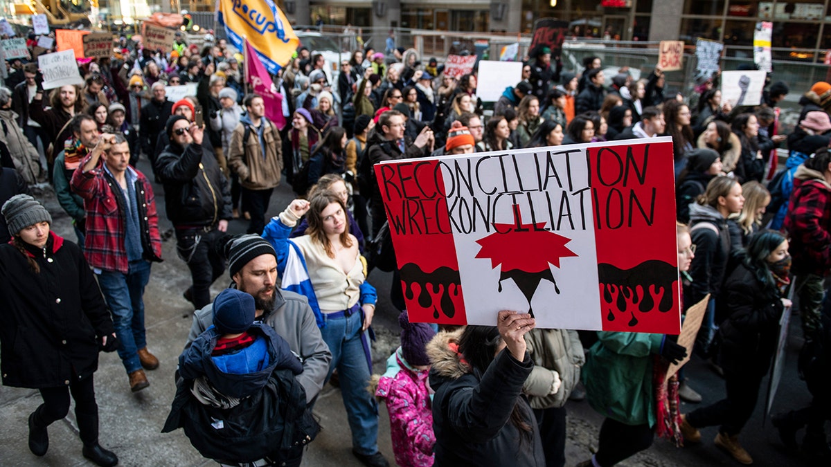 People walk on Kent Street in Ottawa at a rally in solidarity with Wet'suwet'en hereditary chiefs opposed to the Costal GasLink Pipeline, on Monday, Feb. 24, 2020. (Justin Tang/The Canadian Press via AP)