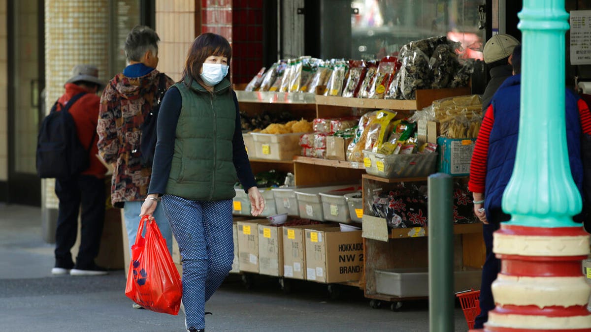 A masked shopper walks in the Chinatown district of San Francisco on Friday, Jan. 31, 2020. 