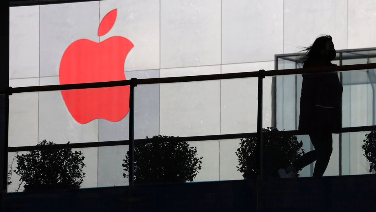 FILE: A woman runs past an Apple logo colored red in Beijing, China. 