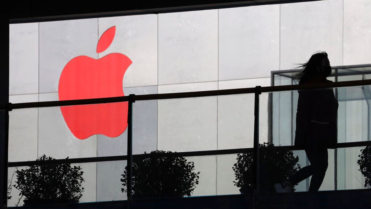 FILE: A woman runs past an Apple logo colored red in Beijing, China.