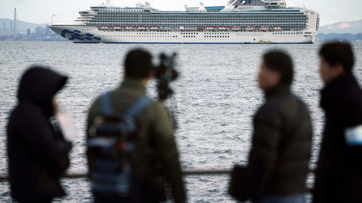 A TV crew film a cruise ship Diamond Princess anchoring off the Yokohama Port Tuesday, Feb. 4, 2020. (AP Photo/Eugene Hoshiko)