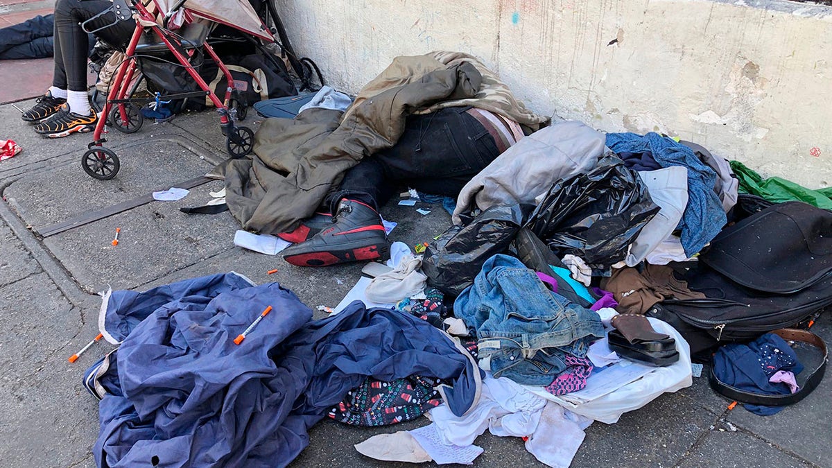 FILE - In this July 25, 2019, file photo, sleeping people, discarded clothes and used needles are seen on a street in the Tenderloin neighborhood in San Francisco. A center for people experiencing methamphetamine-induced psychosis will open in San Francisco as the city struggles with a rise in drug overdoses and rampant street drug use. The San Francisco Chronicle reports the center will open in late spring. (AP Photo/Janie Har, File)