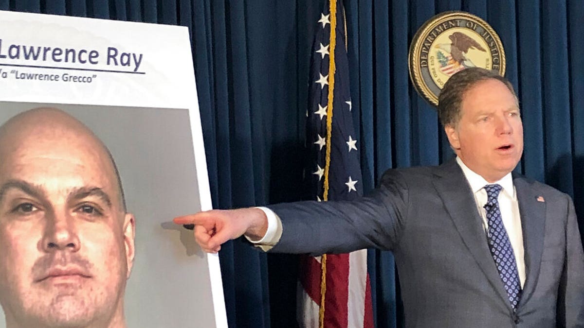 Former U.S. Attorney Geoffrey Berman points to a photo showing Lawrence Ray during a news conference, Tuesday, Feb. 11, 2020, in New York.   College.